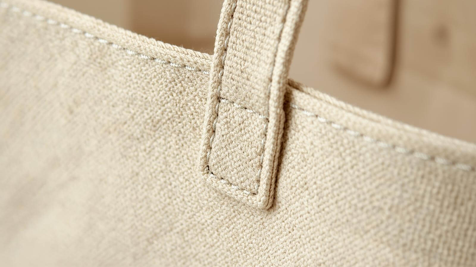 A macro photo showing the clean, uniform stitching on the handle of a canvas tote bag