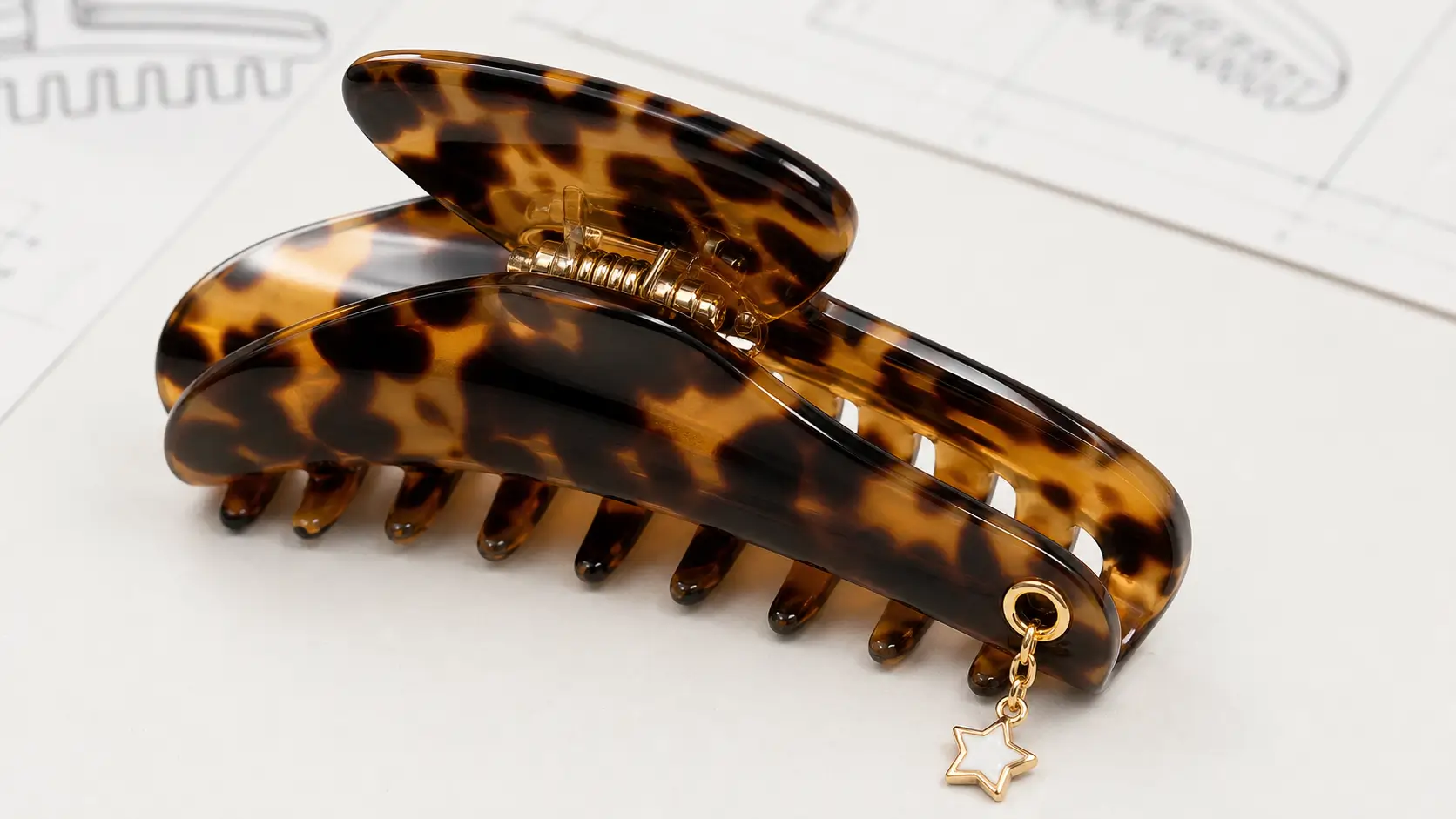 Cellulose acetate claw clip with a short chain and small star charm attached through a reinforced eyelet