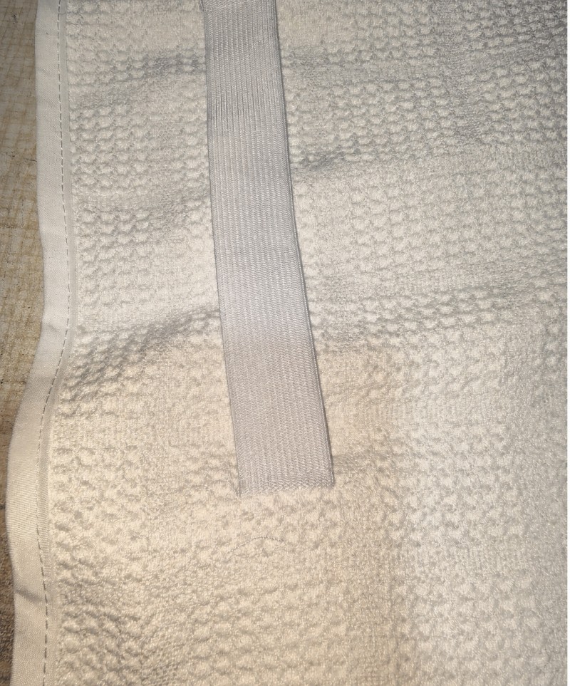 Anonymized close-up of the wide elastic band and binding on a white waffle hair wrap